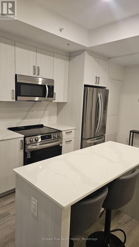 A modern kitchen with stainless steel appliances and white cabinetry.