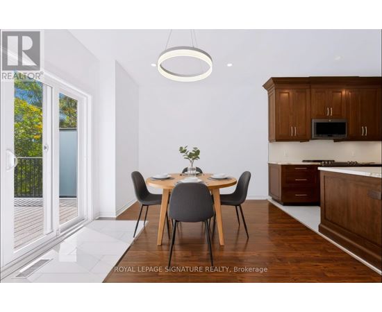 A dining room with a table set for two and a kitchen area in the background.