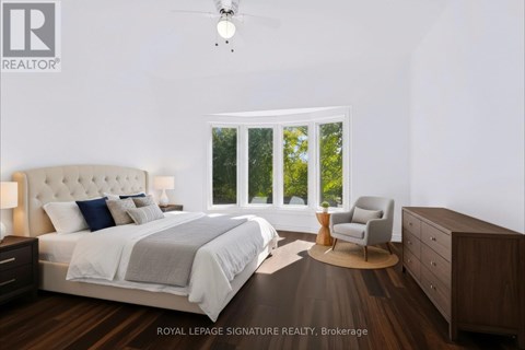 A bedroom with a large bed, a chair, and a ceiling fan.