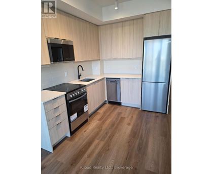 A kitchen with wooden cabinets and a stainless steel refrigerator.