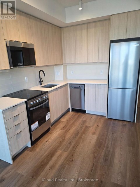 A kitchen with wooden cabinets and a stainless steel refrigerator.