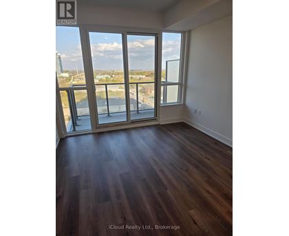 A room with wooden floors and a view of the city through the windows.