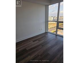 A room with wooden flooring and a large window overlooking a highway.