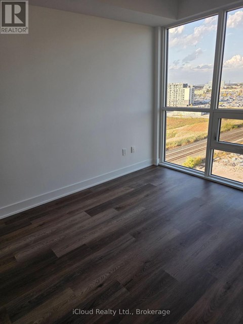 A room with wooden flooring and a large window overlooking a highway.