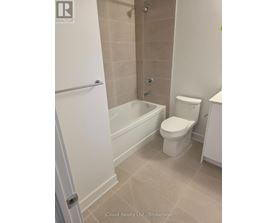 A white toilet sits in a bathroom next to a bathtub.