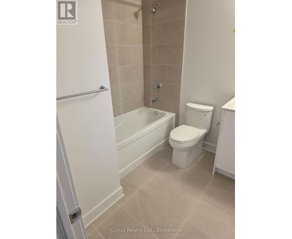 A white toilet sits in a bathroom next to a bathtub.