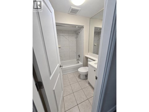 A white bathroom with a toilet, sink and shower.