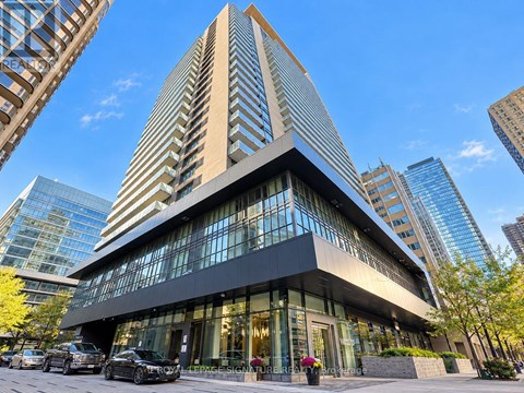 A modern building with a glass facade stands tall among other buildings.