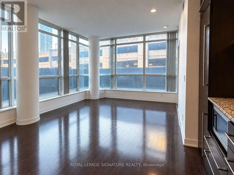 A spacious room with wooden floors and large windows.