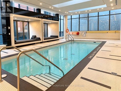 A large indoor swimming pool with a glass divider and a metal ladder.
