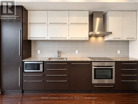 A kitchen with brown cabinets and a black refrigerator.