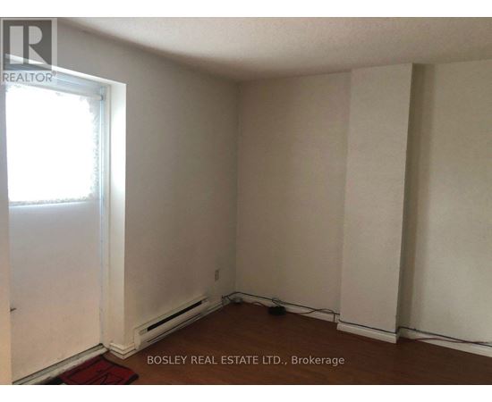 A room with a window and a door, with a sign that says "Bosley Real Estate Ltd., Brokerage".