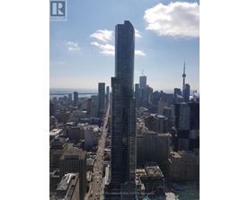 A cityscape with a tall building in the foreground and a bridge in the background.