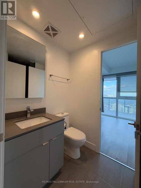 A bathroom with a toilet, sink, and mirror.