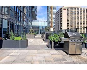 A modern courtyard with a BBQ grill and planters.