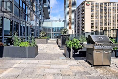 A modern courtyard with a BBQ grill and planters.