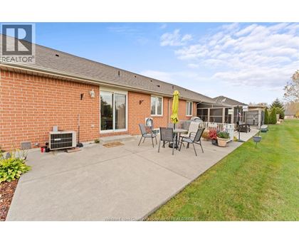 A house with a red brick exterior and a patio with chairs and a table.