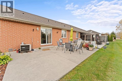 A house with a red brick exterior and a patio with chairs and a table.