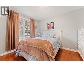 A bedroom with a bed, dresser, and window with curtains.