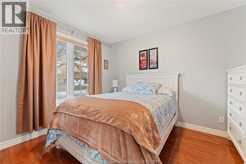 A bedroom with a bed, dresser, and window with curtains.
