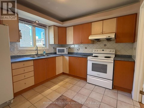 A kitchen with a white stove top oven and brown cabinets.