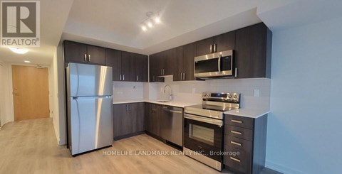 A modern kitchen with dark wood cabinets and stainless steel appliances.