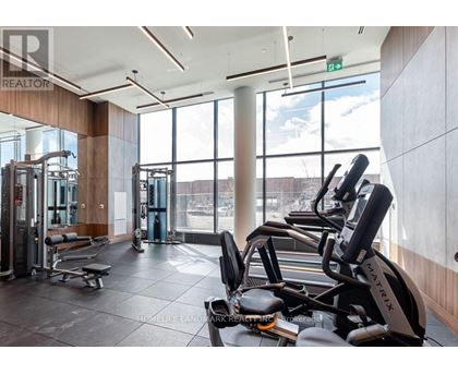 A gym with a row of treadmilers and a row of exercise bikes.
