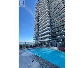 A tall residential building with a swimming pool in front.