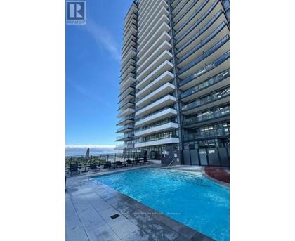 A tall residential building with a swimming pool in front.