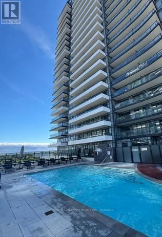 A tall residential building with a swimming pool in front.