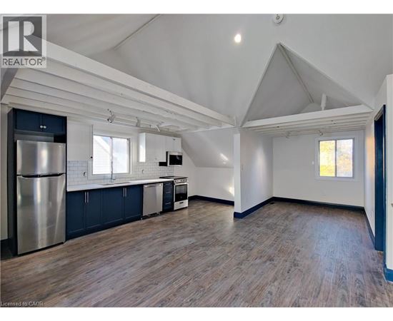 A spacious kitchen with a refrigerator, cabinets, and a window.