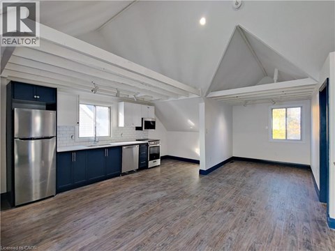 A spacious kitchen with a refrigerator, cabinets, and a window.