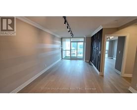 A spacious room with wooden flooring and a large window.