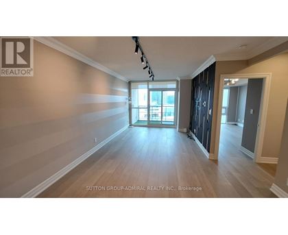 A spacious room with wooden flooring and a large window.