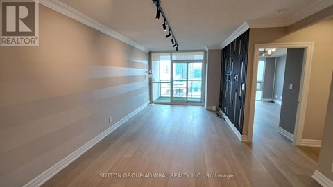 A spacious room with wooden flooring and a large window.