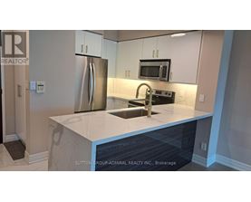 A kitchen with a refrigerator, microwave, and sink.