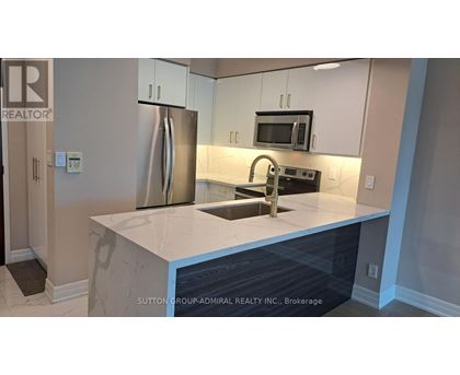 A kitchen with a refrigerator, microwave, and sink.