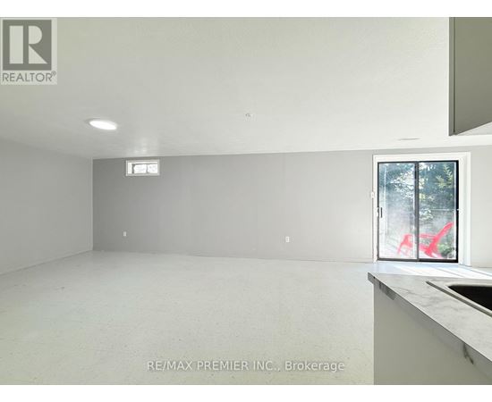 A large empty room with a window and a sink.