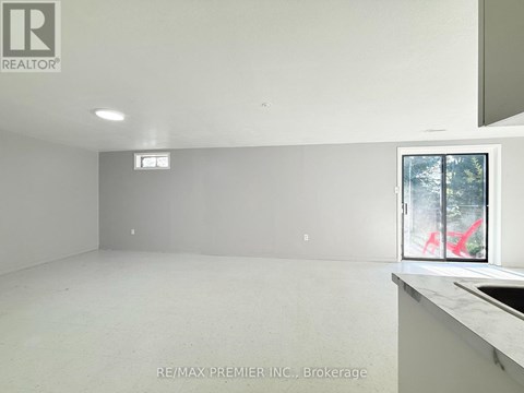 A large empty room with a window and a sink.