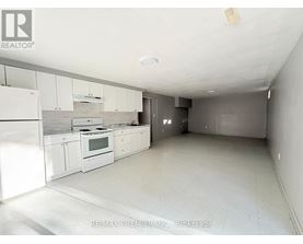 A white kitchen with a re/max premier in-n-out brokerage sign on the wall.
