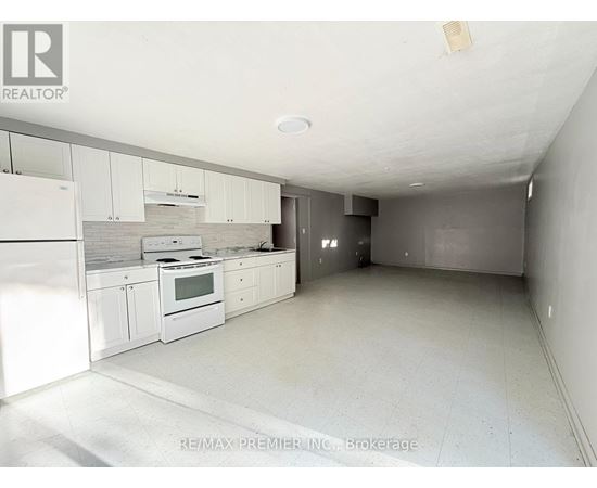 A white kitchen with a re/max premier in-n-out brokerage sign on the wall.