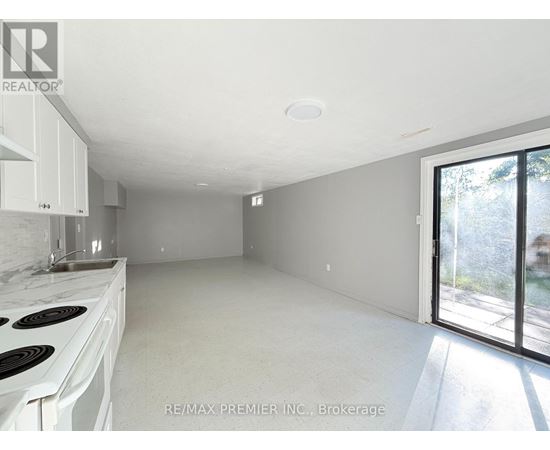 A white kitchen with a stove top oven and a window.