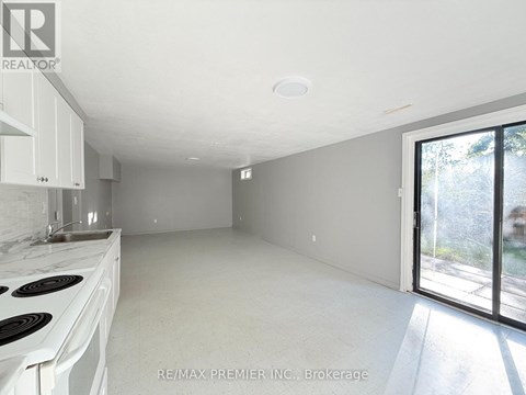A white kitchen with a stove top oven and a window.