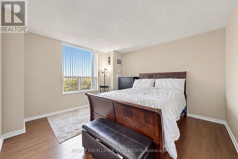 A bedroom with a large bed and a window with blinds.