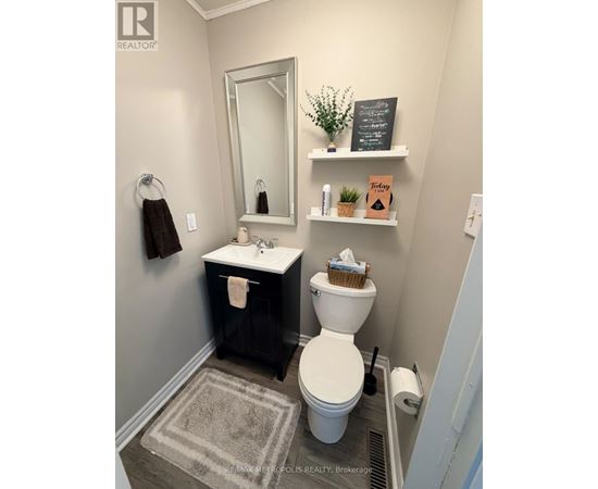 A bathroom with a toilet, sink, and mirror.
