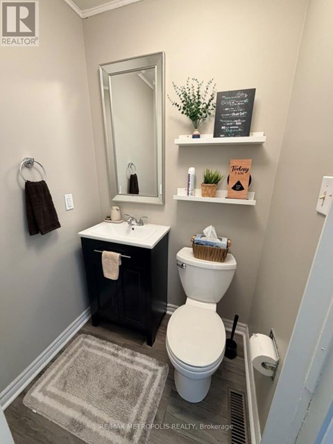 A bathroom with a toilet, sink, and mirror.