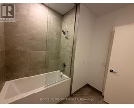 A bathroom with a glass shower door and a white bathtub.