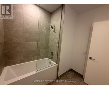 A bathroom with a glass shower door and a white bathtub.