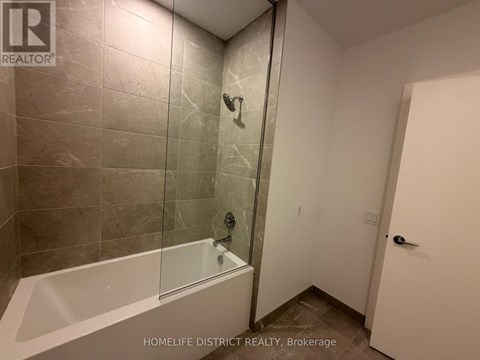 A bathroom with a glass shower door and a white bathtub.