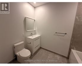 A bathroom with a toilet, sink, and mirror.